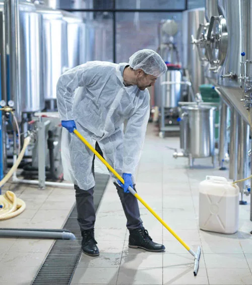 Worker mopping a stainless production kitchen floor