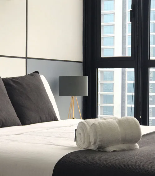 Freshly made hotel bed with rolled towels