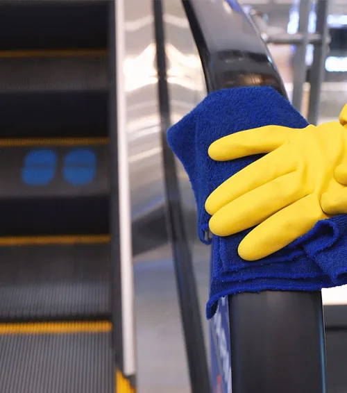 Gloved hand wiping an escalator handrail